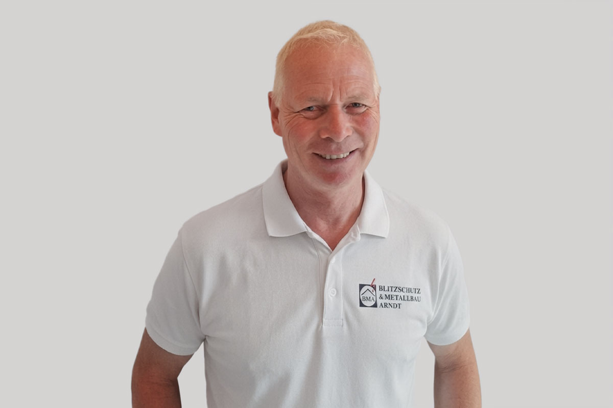 Portrait von Christian Arndt, Inhaber von BMA Blitzschutz & Metallbau Arndt, im weißen Firmen-Poloshirt.